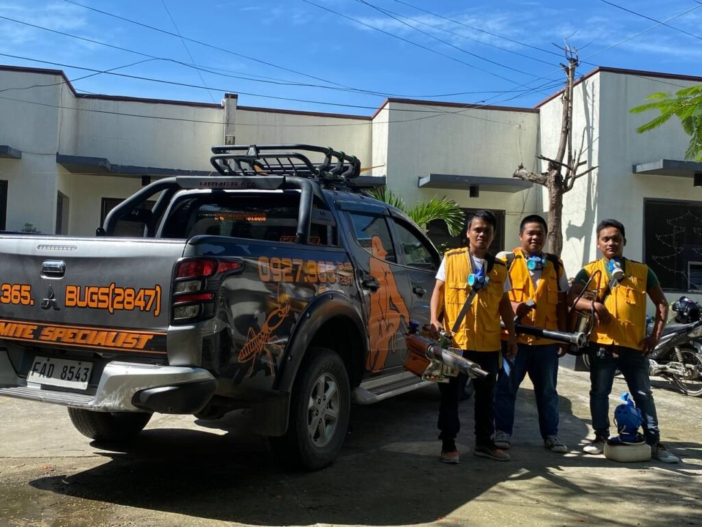 Four Technologist Pest Control professionals stand beside a branded service truck marked “TERMITE SPECIALIST” and the phone number “0927 365 BUGS(2847).” Dressed in yellow safety vests and holding pest control equipment, the team exemplifies readiness and expertise in eco-safe termite-proofing and pest management solutions.