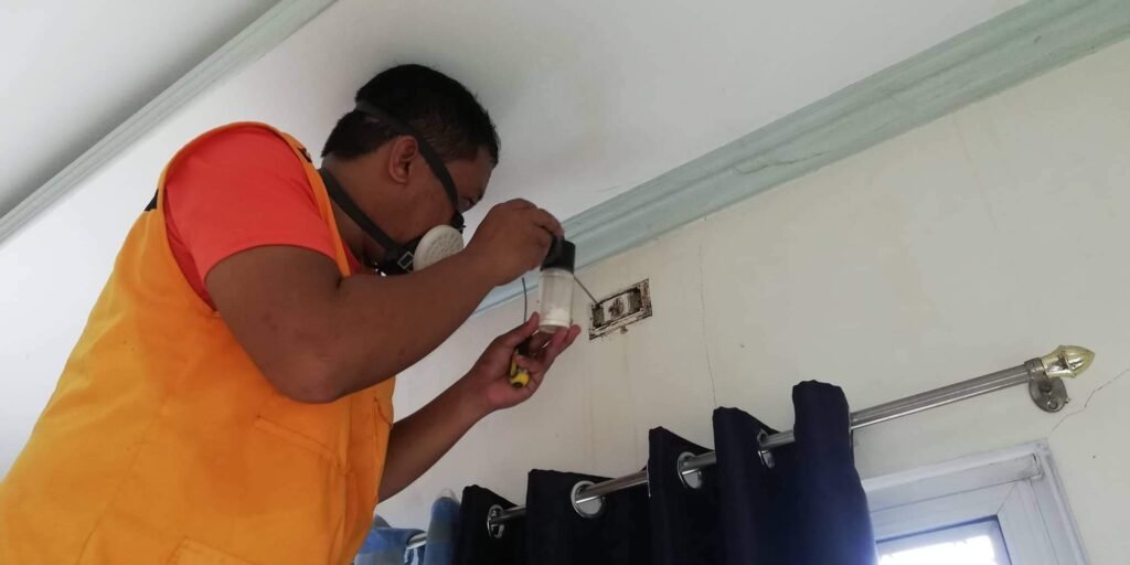 Technologist Pest Control Cebu technician applying Fipronil dust to an electrical outlet infested with termites using a handheld applicator.